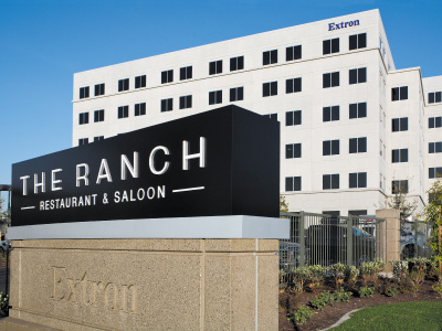 The outside view of THE RANCH Restaurant & Saloon street signs and 6 story Extron building.