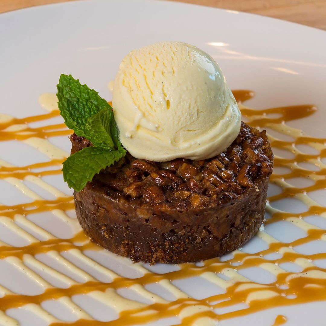 A nutty dessert with ice cream on top and a caramel drizzle.