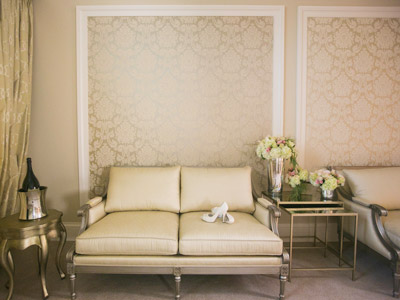 A wall of the Bridal Suite, with a pair of the bride's heels on a creme sofa.