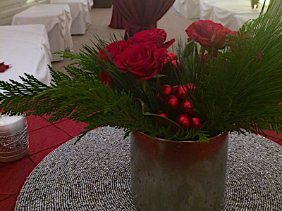 A round table with red and green flowers and a candle on it.