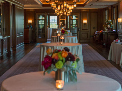 A row of standing tables decorated with candles and floral centerpieces.