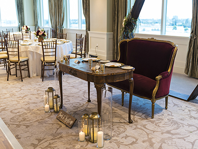 A wide banquet hall view highlighting a wood dance floor centered between symmetrically arranged dining tables and modern circular ceiling fixtures.