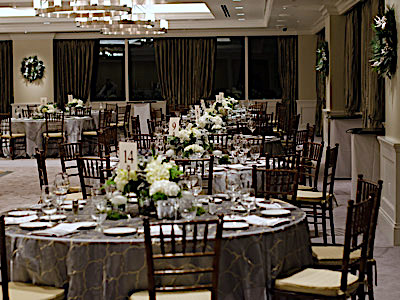 The Great Room set up with grey dining tables and green and white flowers.