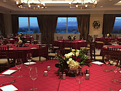 The Great Room set up with red dining tables and red and white flowers.