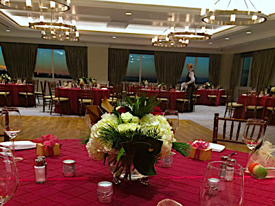 The Great Room set up with red dining tables and red and white flowers, and a dance floor.