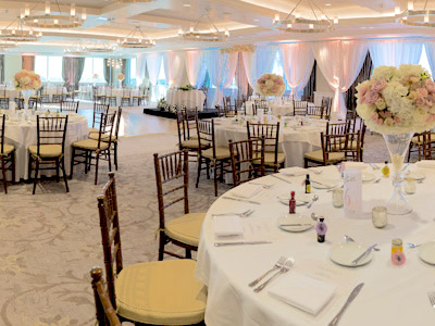 A wideshot of The Great Room set up for a wedding with wooden chairs and rose bouquet centerpieces.