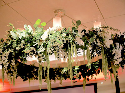 A chandelier with white and green flowers decorating it.