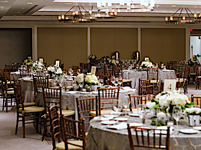 The Great Room set up with grey dining tables and green and white flowers, and a buffet table.