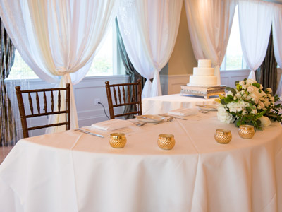A close up of the bride and groom's table, with candles and white rose decorations.
