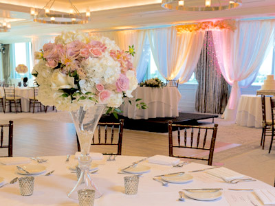 The Great Room set up for a wedding, with the curtains illuminated in pink, gold and blue lights.