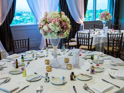 A close up of a guest table with a rose bouquet centerpiece, candles, and small guest favors.