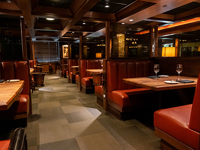 Dining corridor with leather booths, wood-paneled ceiling, and neatly set tables.