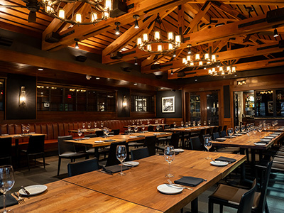 Spacious restaurant interior with long communal tables, leather seating, and warm modern lighting.