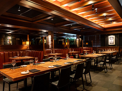 Spacious dining room with neatly set tables, leather seating, and warm wood accents.