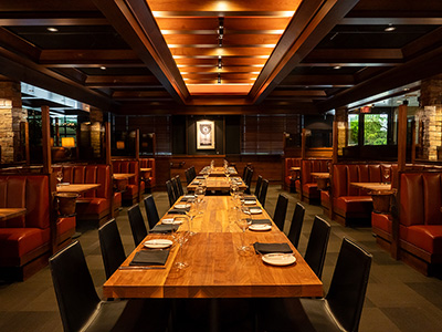Formal dining area with a long wooden table, evenly spaced place settings, and ambient lighting.
