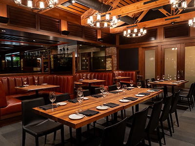 Private dining space with rustic wood beams, chandeliers, and a long table set for a group.