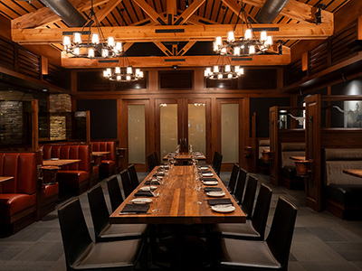 Elegant private dining room with wood-paneled walls, leather seating, and table settings for a large party.