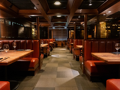 Restaurant aisle lined with leather booths and wooden tables under warm ceiling lighting.
