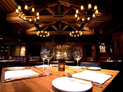 A room with wooden paneling, chandeliers, and looking at a wooden table.