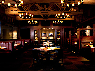 A large room with wooden paneling, chandeliers, private dining room, and wooden tables.