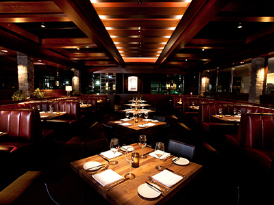 A room with wooden paneling, leather booth seating, and a row of wooden tables.