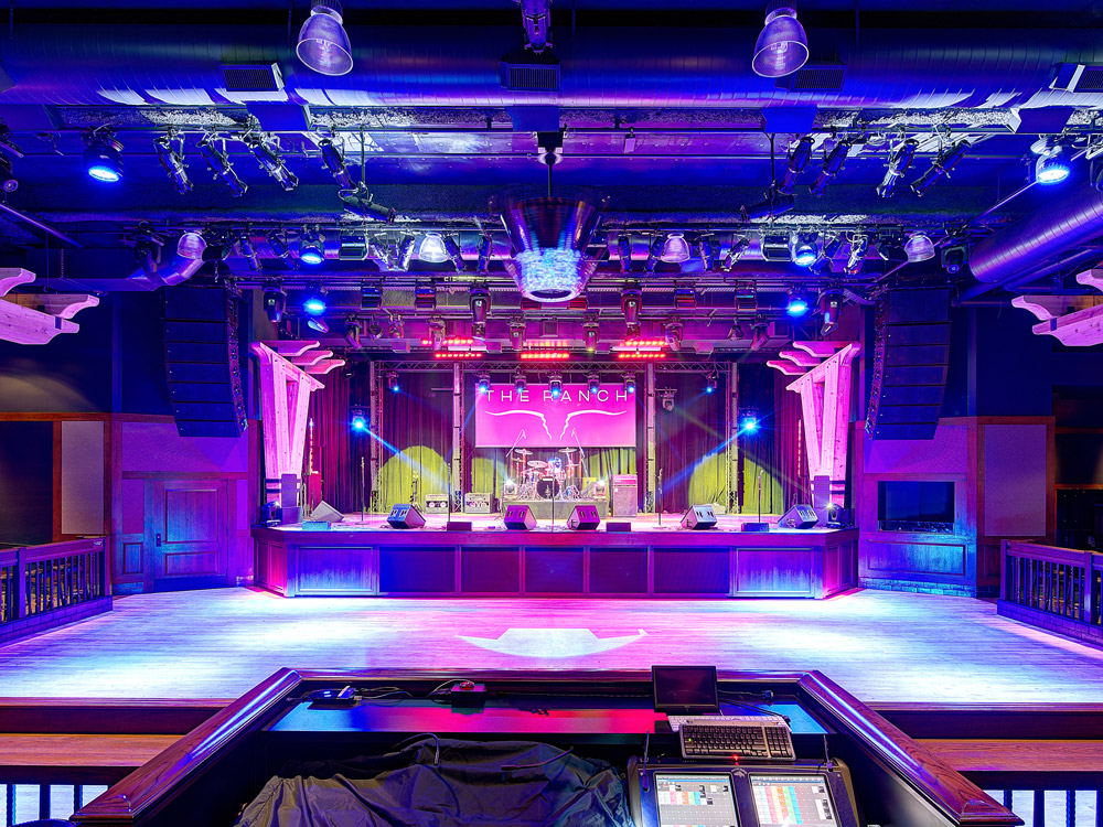 A view of the Saloon dance floor with purple and blue lighting on the stage.