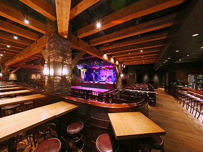 Inside the Ranch Saloon showing a wooden dance floor, stage, guitar disco ball, tables and chairs, and booth seating.