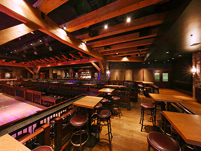 Inside the Ranch Saloon showing a wooden dance floor, tables and chairs, booth seating, and a bar.