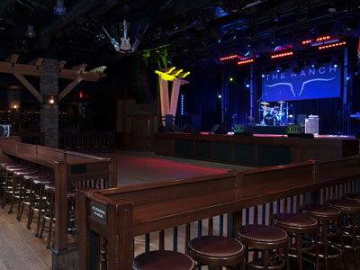 2 rows of stools around a dance floor, looking at a stage set with band equipment