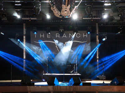 The stage with blue and white lights, microphones, sound equipment, and guitar disco ball